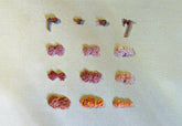 Assorted small yarn balls on a textured beige surface showing color of Rubia tinctorum (madder) natural dye